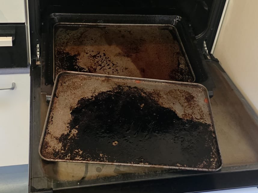 Oven trays heavily baked with burnt-on grease before cleaning